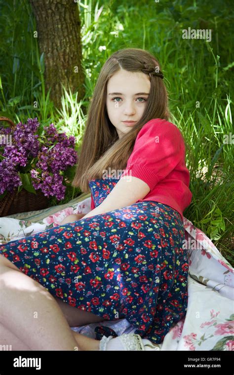 Beautiful Teenage Girl Sitting On A Blanket In A Long Grass Stock Photo