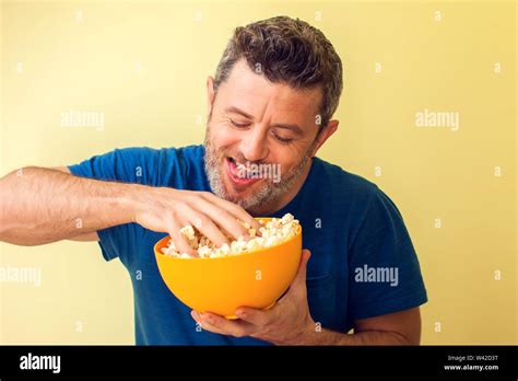 Portrait Of A Funny Man Eating Popcorn Over Yellow Background Stock