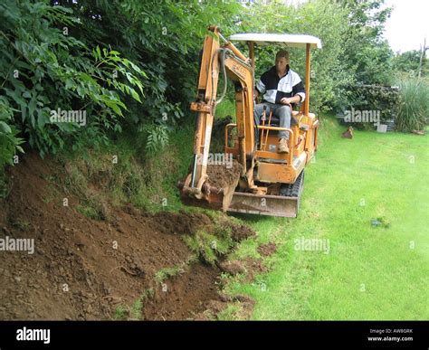 Digger Small Caterpilar Digging Trench In Green Field For Planting