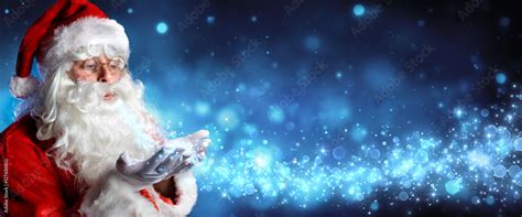 Santa Claus Blowing Magic Christmas Stars In Snowy Night Stock Photo
