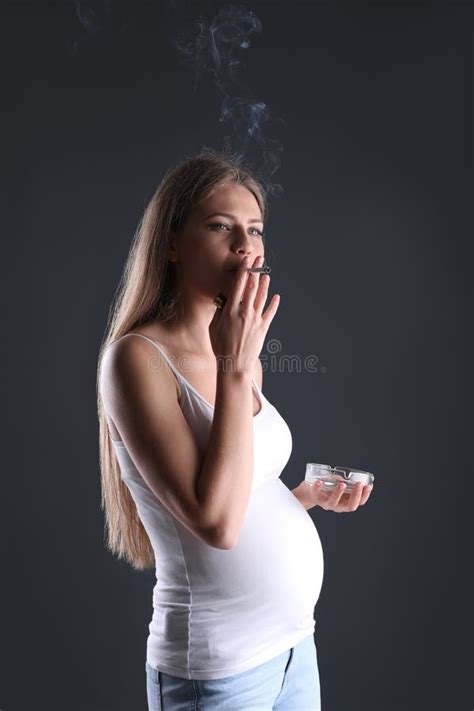 Cigarrillo Que Fuma Joven De La Mujer Embarazada En Fondo Oscuro Foto