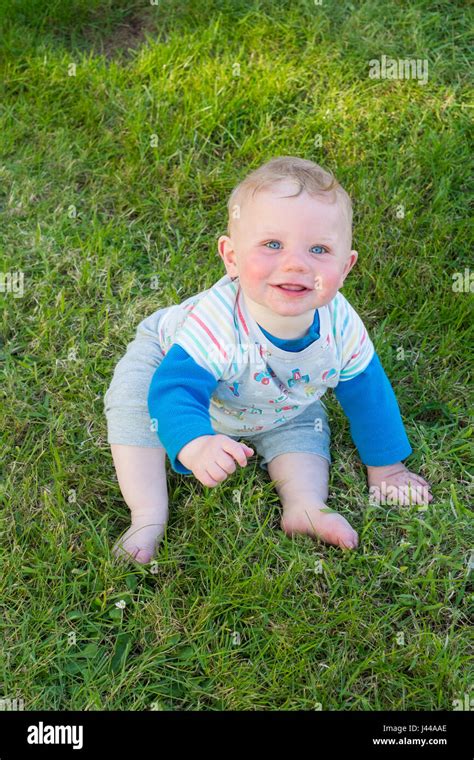 Eight Month Old Baby Boy Smiling And Sitting On The Grass South Devon England United Kingdom