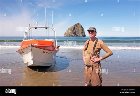 A Dory Fisherman Stands Near His Boat On The Beach At Pacific City