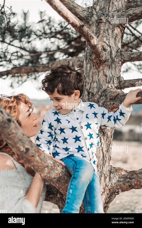 Mom Holding Her Toddler Son While He Is Sitting On A Tree Love And