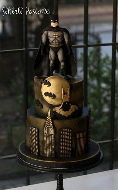 A Three Tiered Cake With Batman Figurines On Top And Cityscape In The