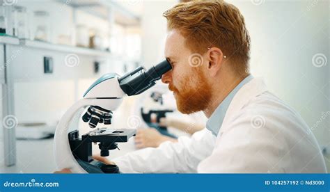 Jeune Scientifique Regardant Par Le Microscope Dans Le Laboratoire