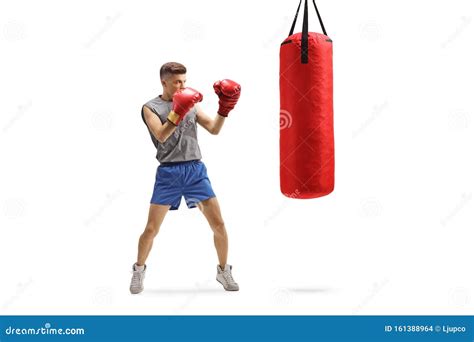 Young Guy Punching With Boxing Gloves In A Red Hanging Bag Stock Photo