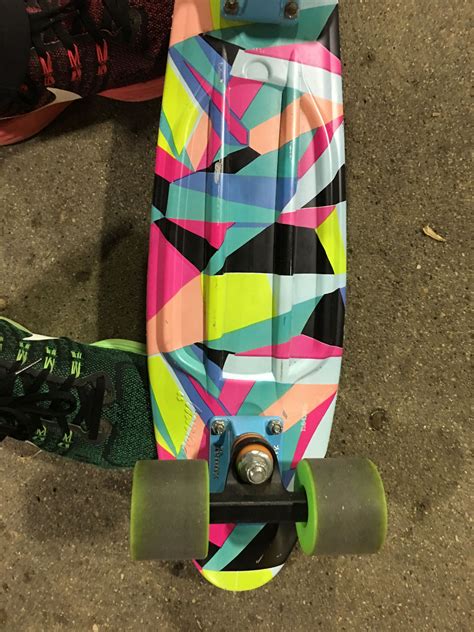 A Colorful Skateboard Laying On The Ground Next To Someones Feet And Shoes
