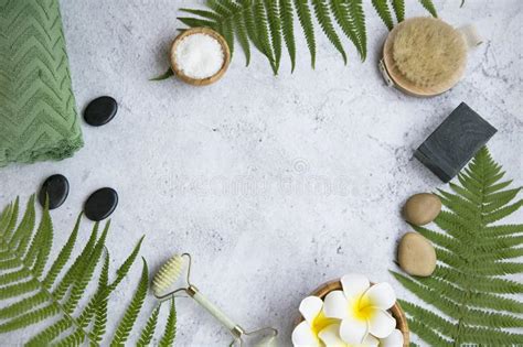 green botanical spa flatlay with fern charcoal soap massage stones frangipani flowers and