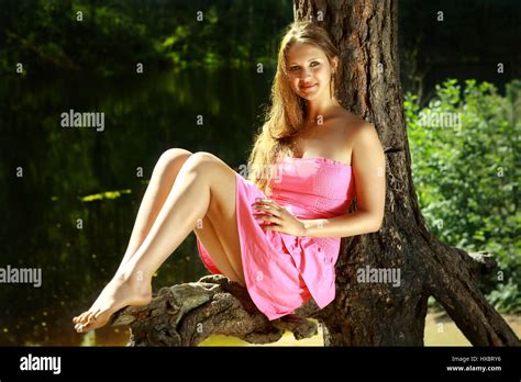 girl caucasian appearance 16 years old in a pink dress with long hair and bare feet sitting
