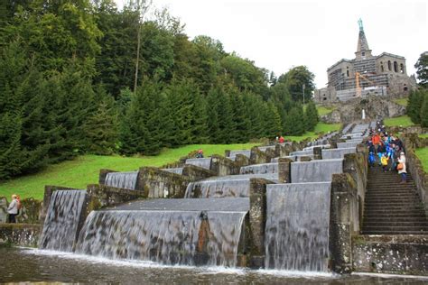 Many People Are Walking Up And Down The Stairs To A Waterfall That Is