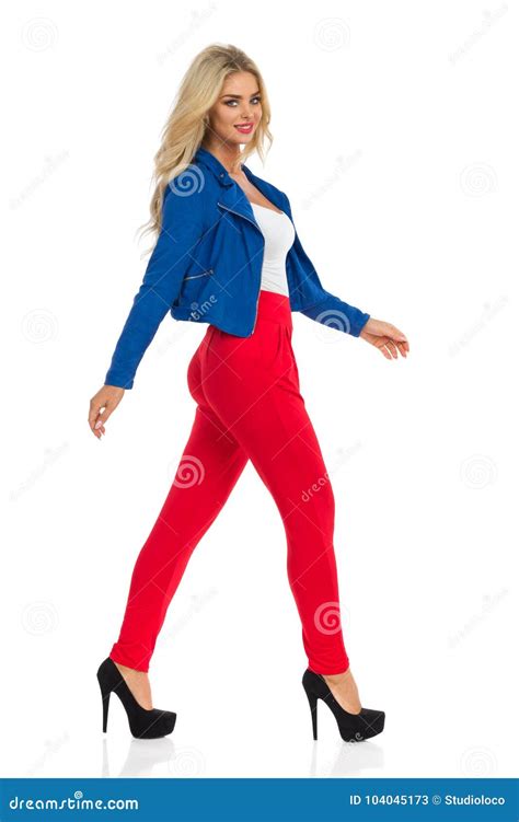 seksowna blond kobieta chodzi w kurtce rewolucjonistek spodniach i szpilkach obraz stock