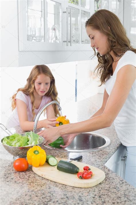 Tienes que invertir en política. niña ayudando a su madre para lavar las verduras en la ...