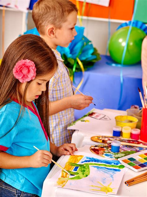 Little Girl And Boy With Brush Painting In Kindergarten Stock Photo