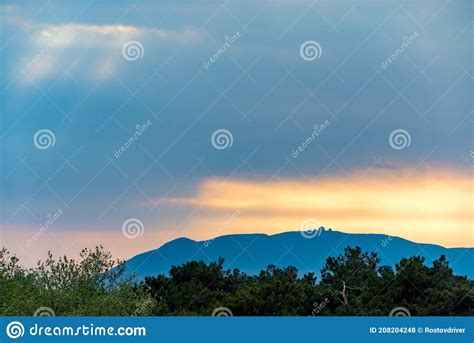 Colorful Sunset Sky Over Silhouette Of Black Forest Hills And Mountains