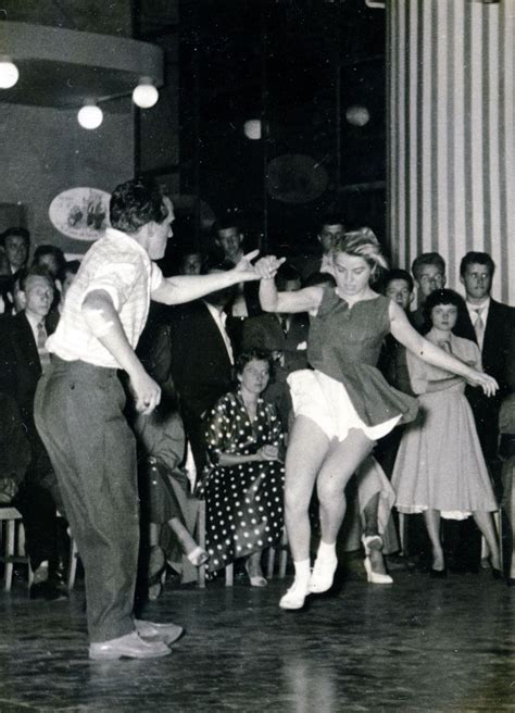 An Old Photo Of Two People Dancing In Front Of A Group Of People With