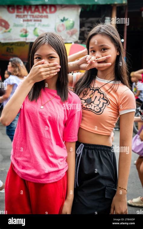 Two Young Filipino Girls Make A Cheeky Pose And Hand Signal During A Religious Festival In
