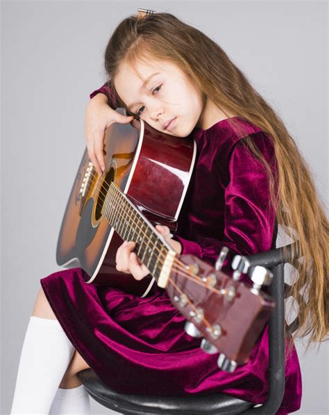 Free Little Girl Playing Acoustic Guitar On Chair Nohatcc