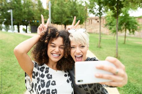 Two Young Girl Making A Selfie With Their Smartphones By Guille