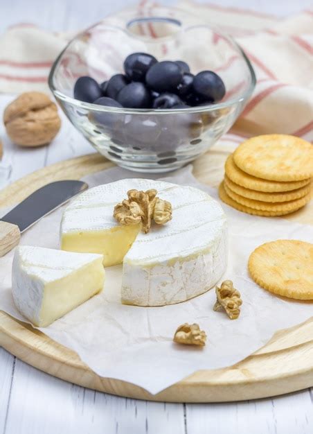 Premium Photo Soft Brie Cheese With Crackers Nuts And Olives