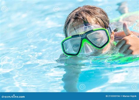 Child Swimming In A Pool With Goggles On Showing Thumbs Up Gesture