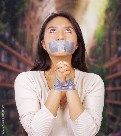 Young Brunette Woman Wearing White Sweater Gagged And Tied With Duct Tape Around Wrists Facing