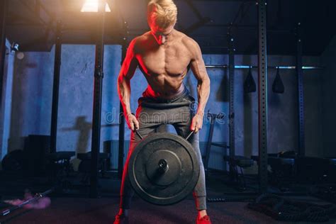 Caucasian Fitness Man Lifting Heavy Plate Of Barbell During Workout In