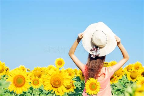 Young Girl In A Hat In A Field Of Sunflowers In The Summer The View