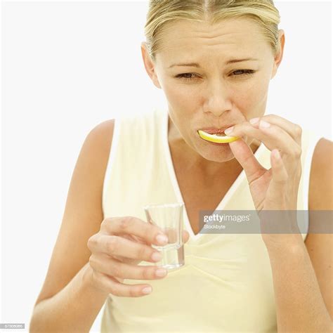 Young Woman Sucking On A Lemon Wedge After A Shot Of Tequila High Res