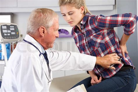 Teenage Girl Besuche Arztpraxis mit Rückenschmerzen Stock Bild