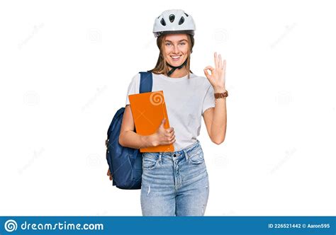 Beautiful Young Blonde Woman Wearing Backpack And Bike Helmet Doing Ok Sign With Fingers