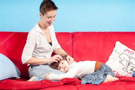 madre e hija pequeña abrazándose en el sofá 2022