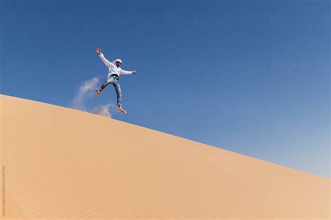 Man Jumping From Sand Dunes In The Desert Del Colaborador De Stocksy
