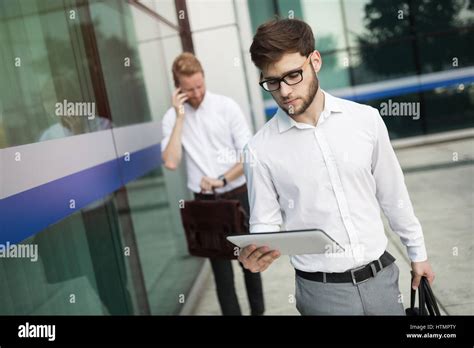 Business People Walking Outdoors And Using Phones Tablets Stock Photo