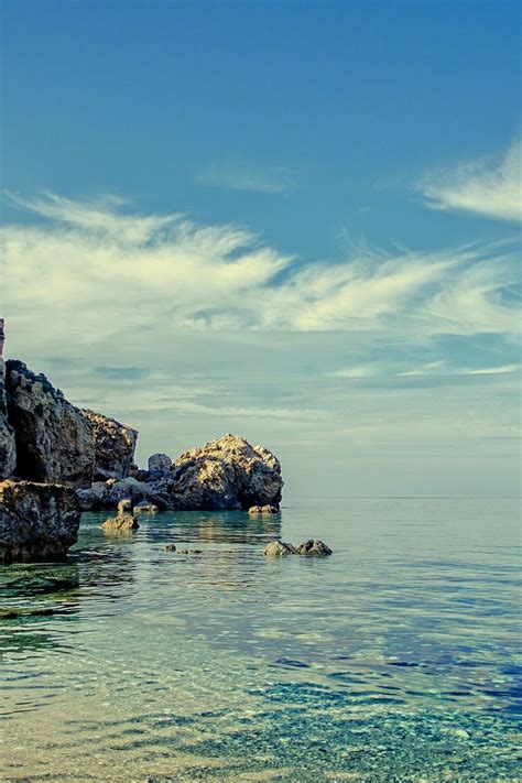 Cliff And Rock Formations On Calm Body Of Water During Daytime Violet