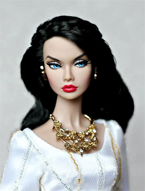A Close Up Of A Doll Wearing A White Dress With Gold Jewelry On Her Neck