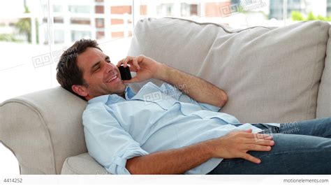 Casual Man Lying On The Sofa Chatting On The Phone Stock Video Footage