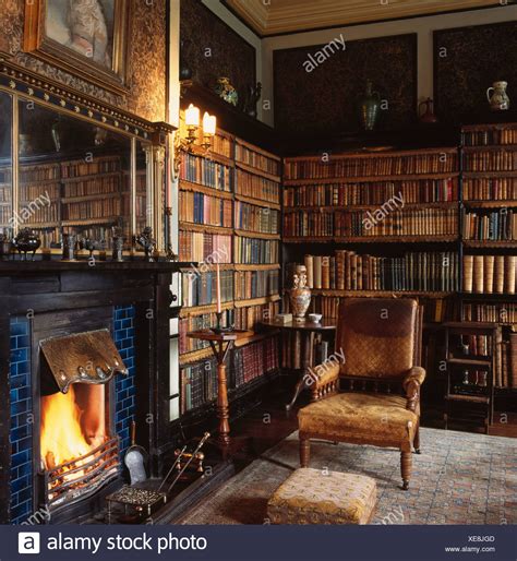 Old Worn Leather Armchair Beside Fireplace In Country House Library