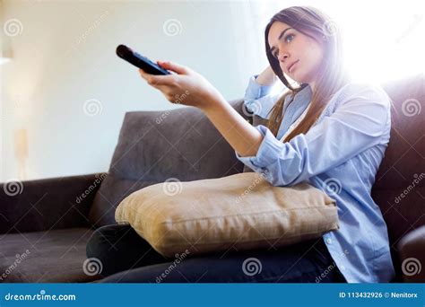Beautiful Bored Young Woman Watching Tv And Holding Remote Control At