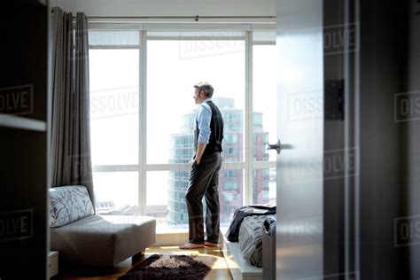 Man Looking Out Of High Rise Apartment Window Stock Photo Dissolve