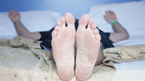 The Feet Of A Man On The Bed Hes Trying To Sleep He Puts A Pillow