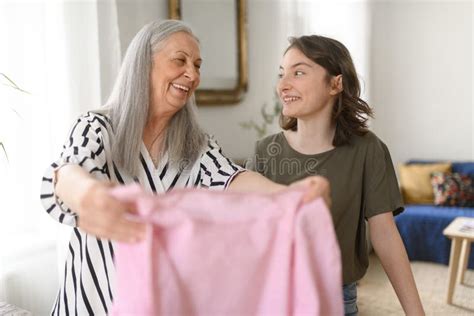 Teenage Girl Ironing And Helping With Household Chores Her Senior Grandmother At Home Stock