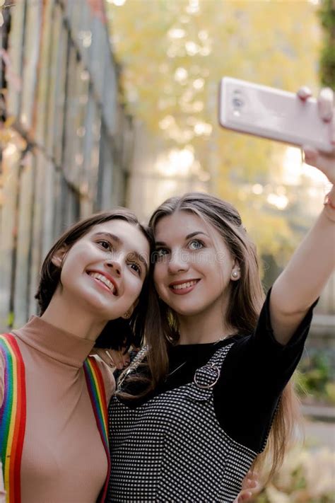 Two Beautiful Girls Taking Selfie On The Phone In The Autumn Park Stock