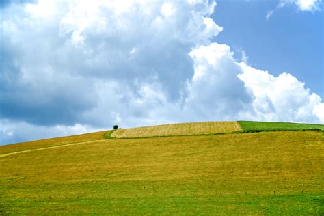 Green Grass Covered Mountain Under White And Blue Skies · Free Stock Photo