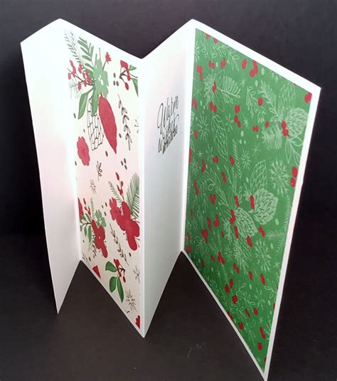 An Open Christmas Card With Holly And Red Berries On It In Front Of A