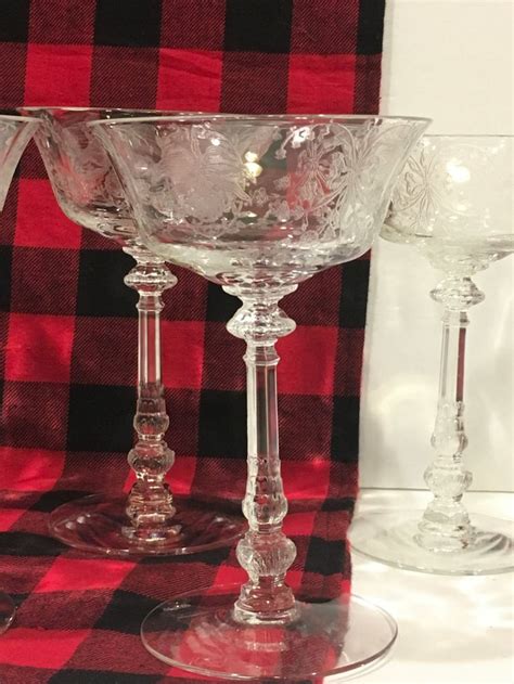 three glass goblets sitting on top of a red and black checkered tablecloth