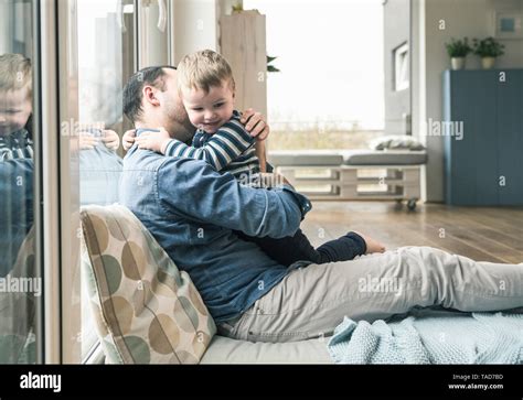 Father Cuddling With Son At Home Stock Photo Alamy