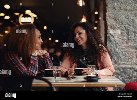 Two Women Discussing At A Restaurant Smiling Young Friends Sitting In