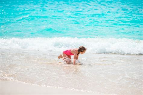 Adorable niña en la playa divirtiéndose mucho en aguas poco profundas Foto Premium