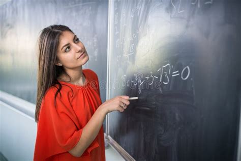 Pretty Young College Studentyoung Teacher Writing On The Chalkboard